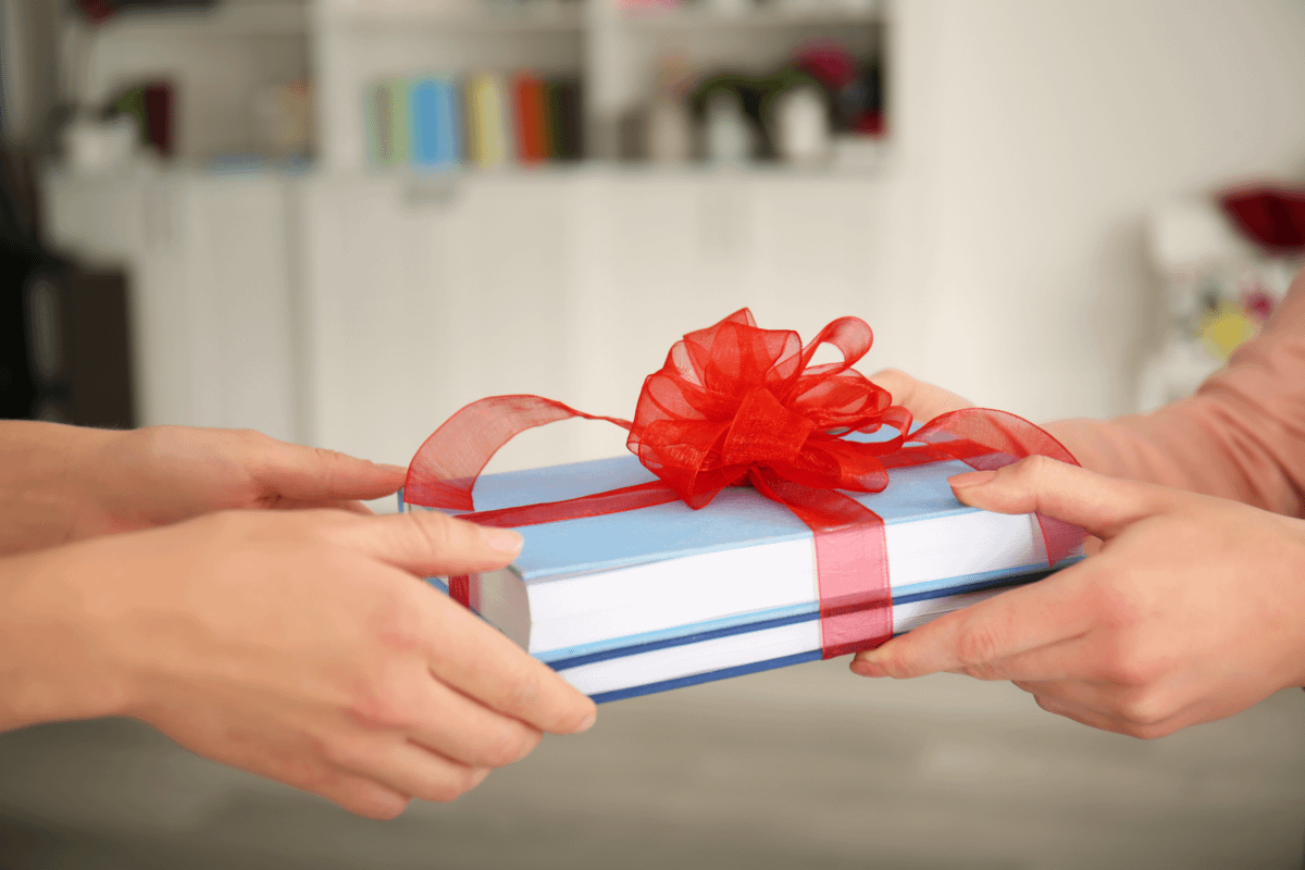 A person giving a book as a gift to another person