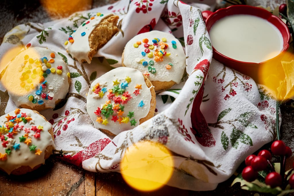 An assortment of frosted Italian Christmas cookies decorated with sprinkles in a basket