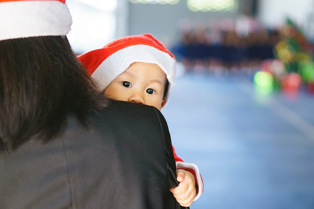 Mother holding 11 months old baby in Santa suit