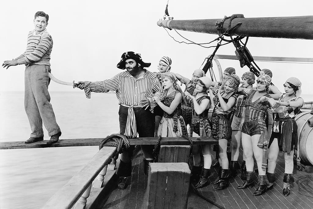 Group Of Pirates Trying To Push A Young Man Over A Plank