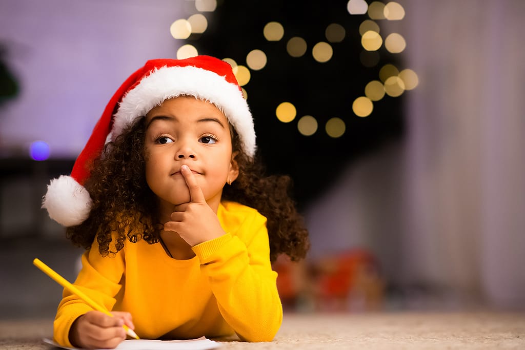 A little girl writes a Wish List before her video call with Santa