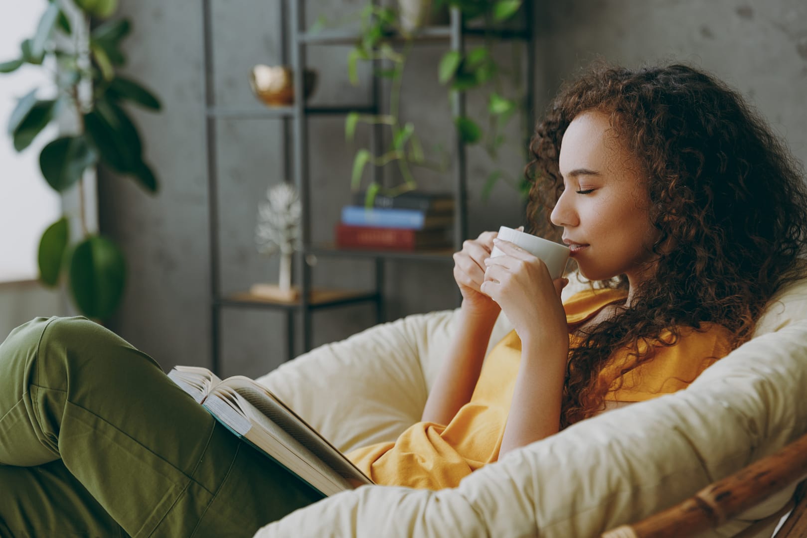 A person reading a book in a comfortable chair with a cup of tea