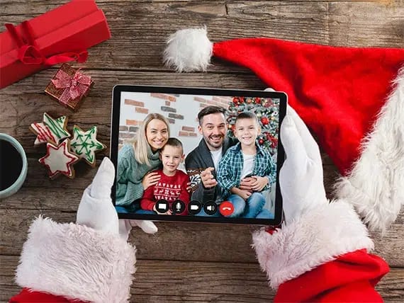 A pair of Santa hands hold a tablet and we see a family having a FaceTime with Santa